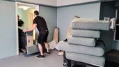 Dos personas sacando un mueble de una habitación 
