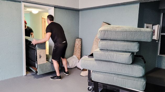 Dos personas sacando un mueble de una habitación 