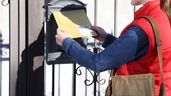 Una cartera metiendo una carta en un buzón 