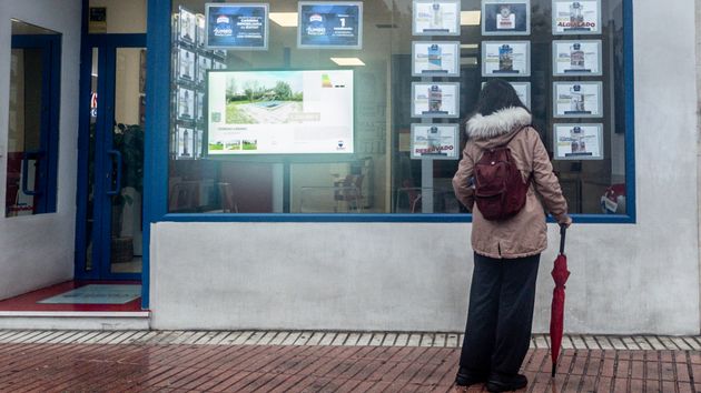 Mujer mirando carteles en una inmobiliaria
