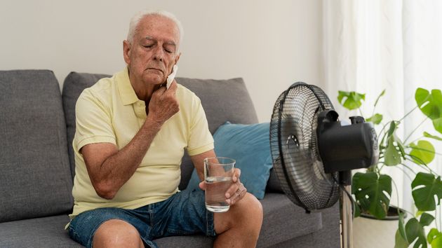 Un hombre con calor frente a un ventilador