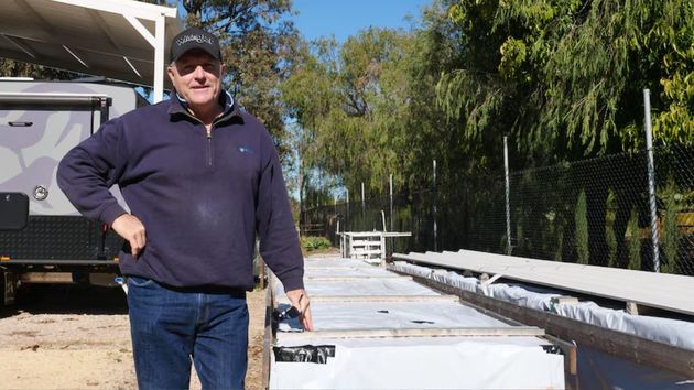 Una imagen del hombre junto a su casa prefabricada sin montar