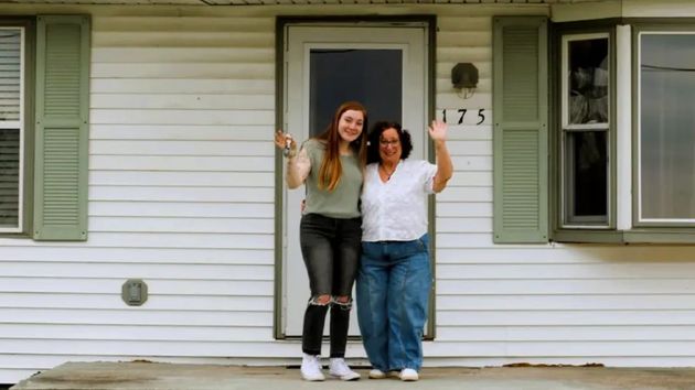 La joven junto a su abuela en la puerta de la vivienda 