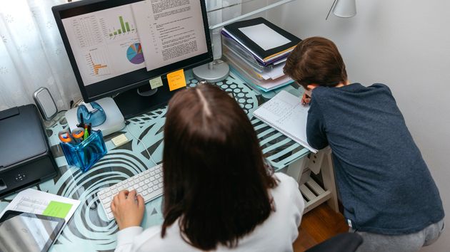 Una madre teletrabajando con su hijo al lado