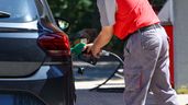 Una persona repostando gasolina en un coche, en una gasolinera