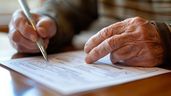 Las manos de un anciano firmando un documento