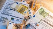 Dos bombillas sobre billetes, monedas y facturas