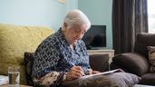 Una anciana firmando un documento 