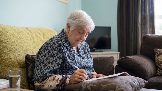 Una anciana firmando un documento 
