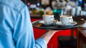 Un camarero de espaldas llevando dos cafés