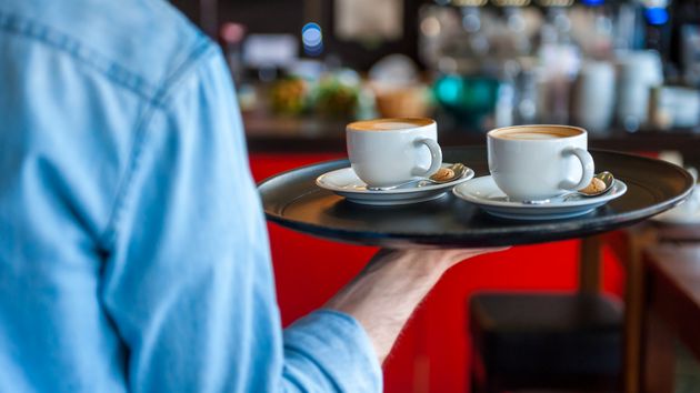 Un camarero de espaldas llevando dos cafés