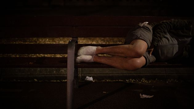 Un hombre durmiendo en el banco de un parque