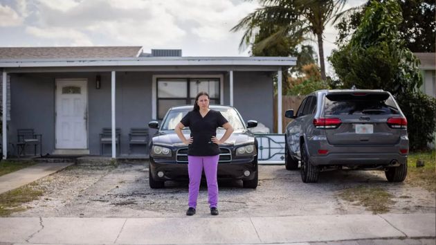 La mujer juntos junto a los coches aparcados frente a su casa