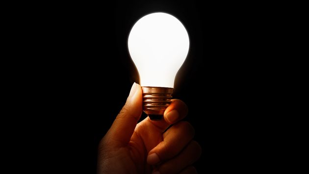 Una mano sujetando una bombilla encendida