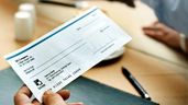 La mano de una persona sujetando un cheque 