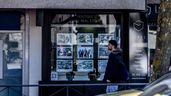 Joven pasando delante de un cartel de inmobiliaria
