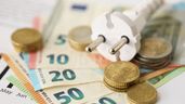 Un enchufe junto a billetes y monedas de euro