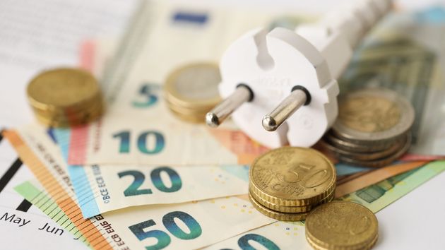 Un enchufe junto a billetes y monedas de euro