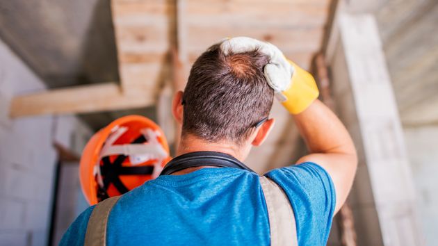 Un trabajador de espaldas echándose la mano a la cabeza
