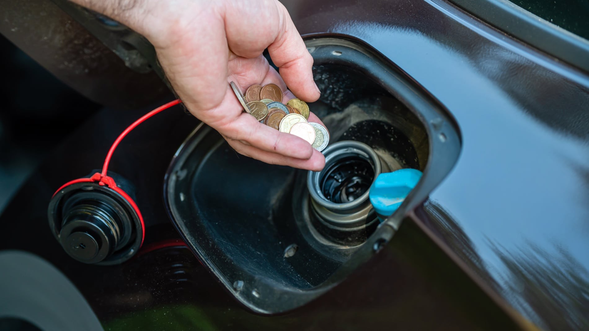 Gasolineras más baratas cerca de ti echando monedas euros dentro depósito gasolina