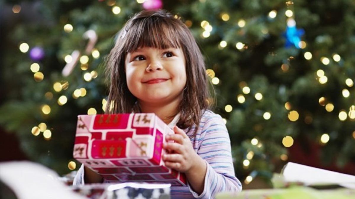Niña con un regalo de Navidad Cruz Roja, Alcampo y Cáritas reciben donaciones de juguetes para Navidad
