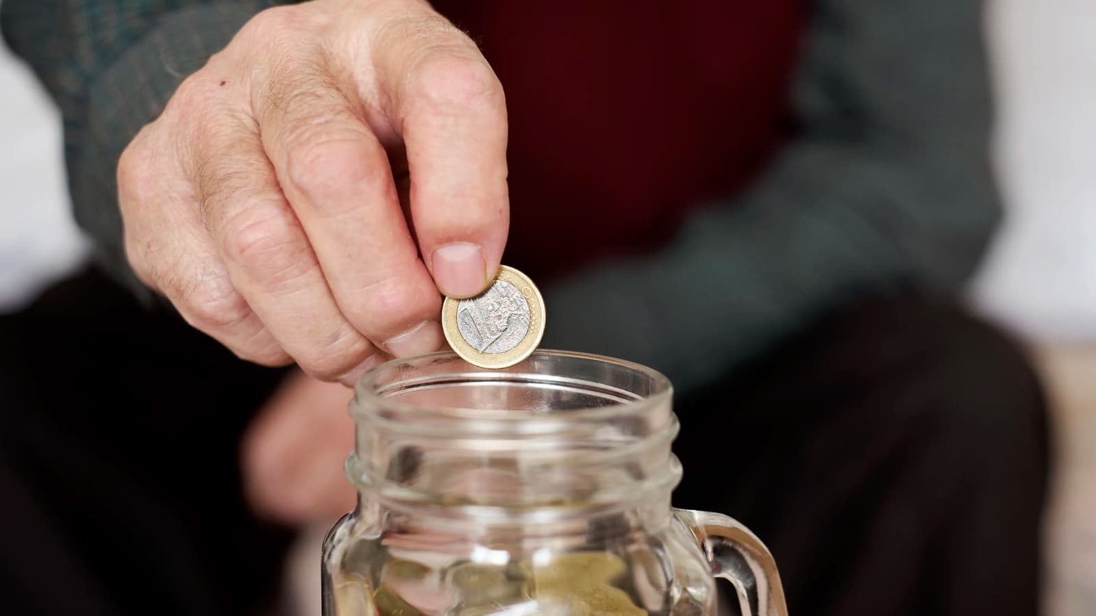 hombre echa un euro en su hucha