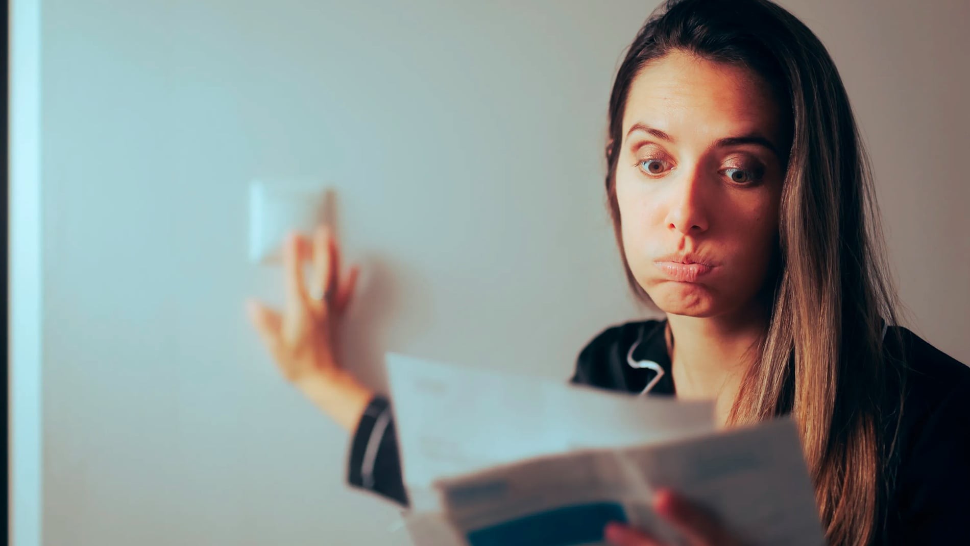 mujer apaga la luz después de ver la factura