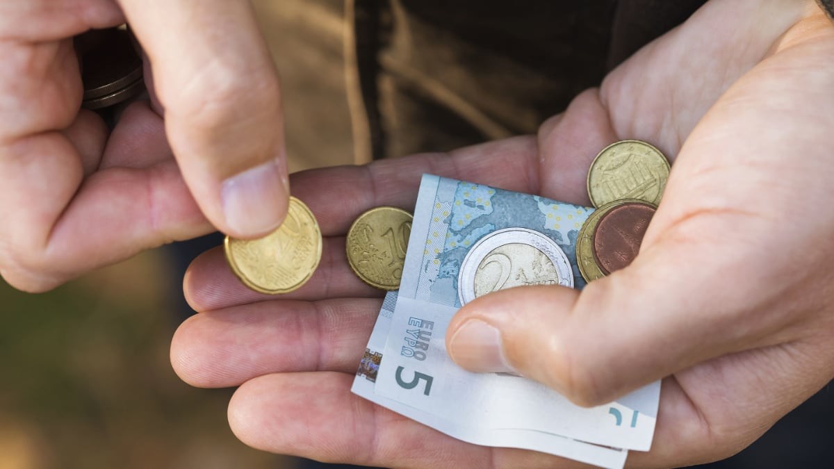 persona con monedas y billetes de euro