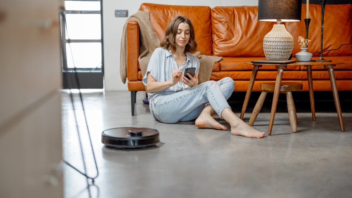 Precio de la luz viernes, 12 de mayo de 2023. mujer pasa aspiradora con el movil