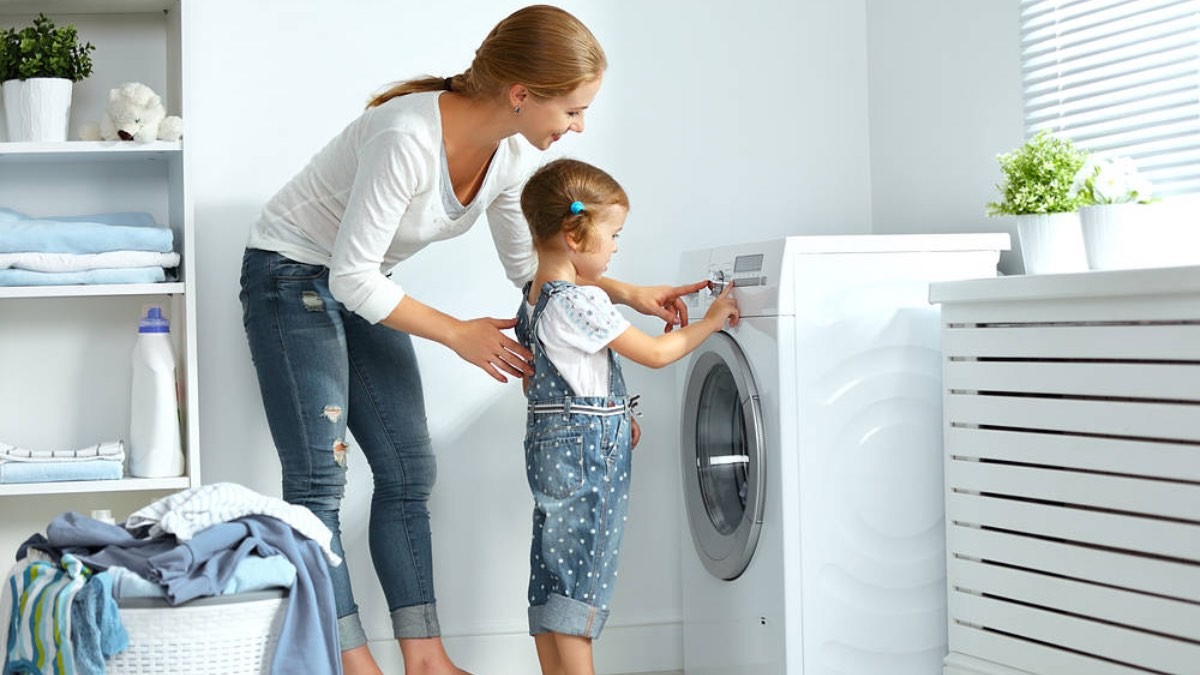 una mujer pone la lavadora con su hijo