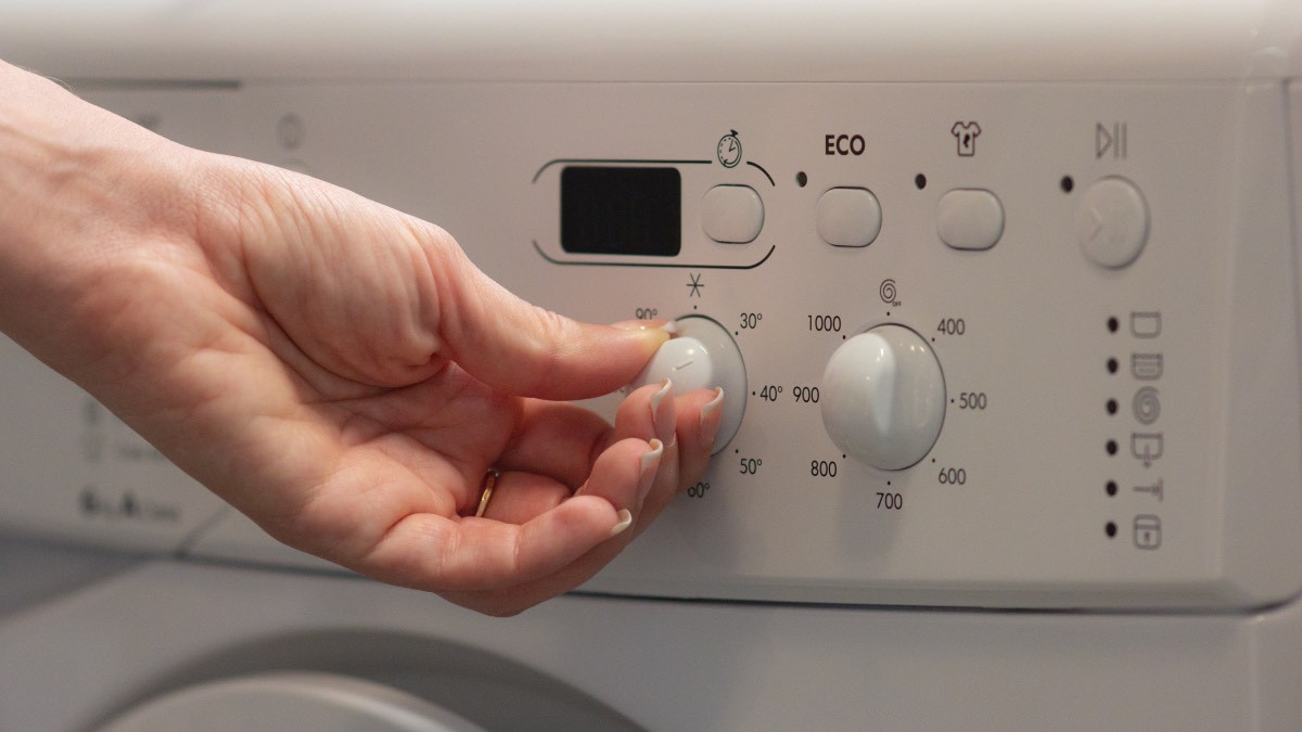 una persona pone en marcha la lavadora