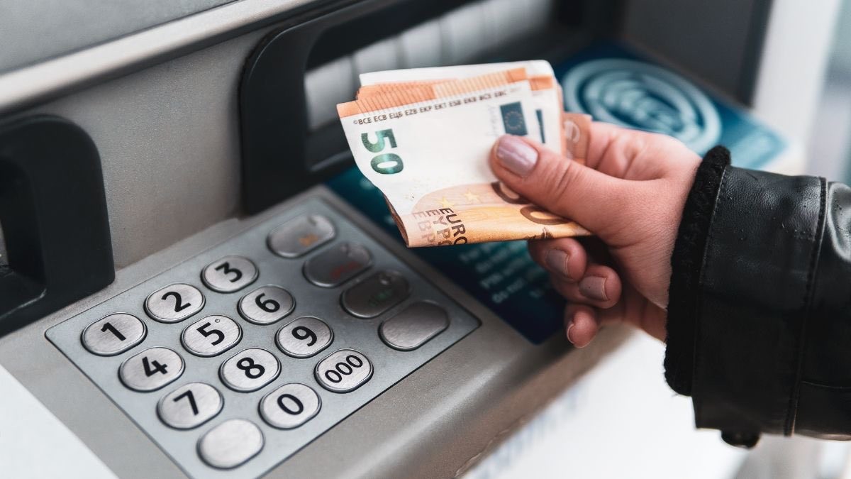 Fecha de cobro del Ingreso Mínimo Vital en septiembre de 2023: día de cada banco persona sacando euros del cajero