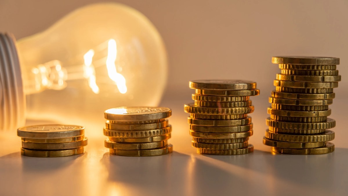 Una bombilla encendida junto a monedas de euro