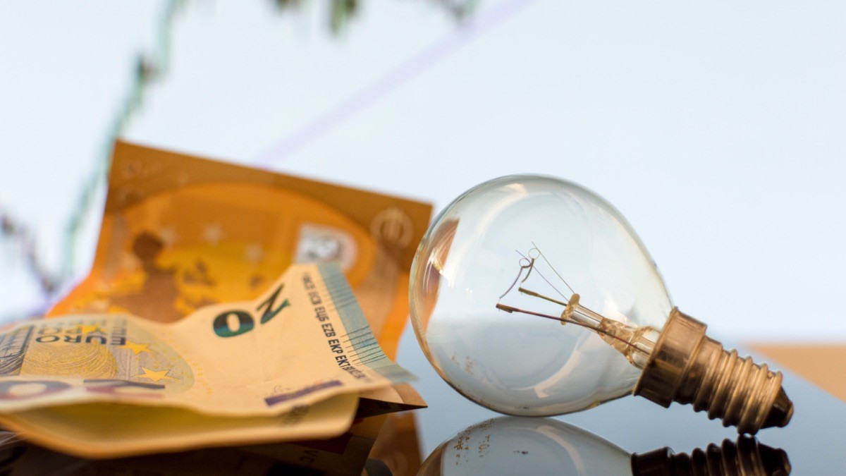 El precio de la luz el miércoles, 9 de agosto de 2023 bombilla junto a varios billetes de 20 euros