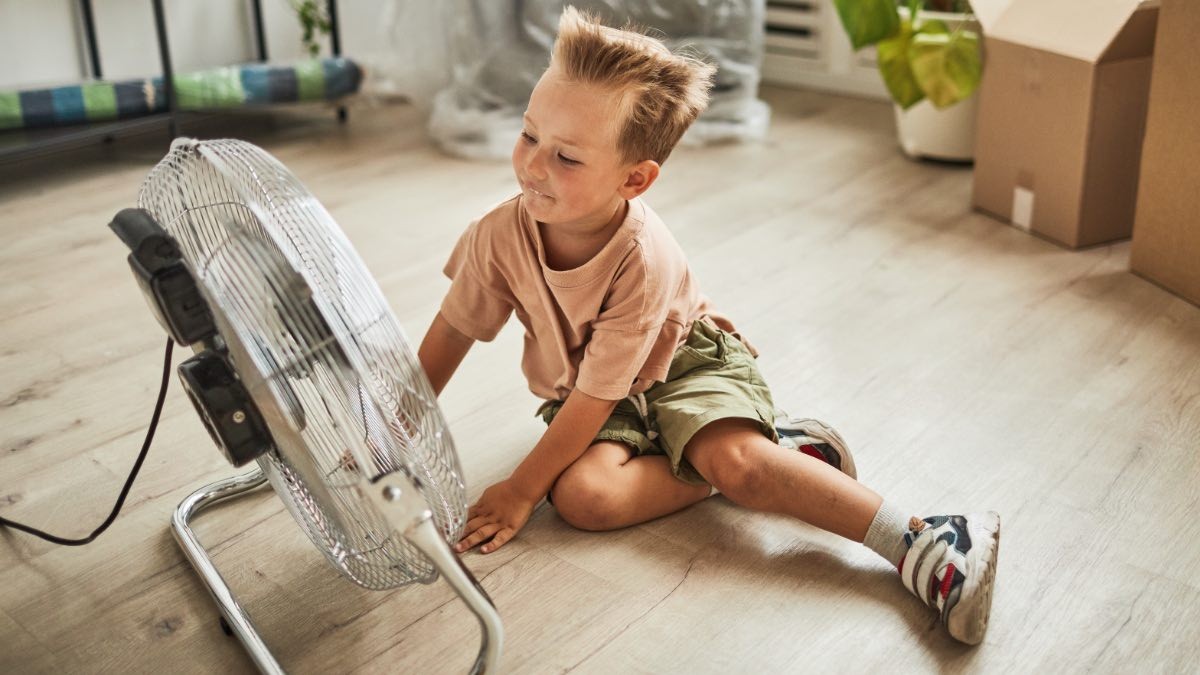 un niño refrescándose con un ventilador
