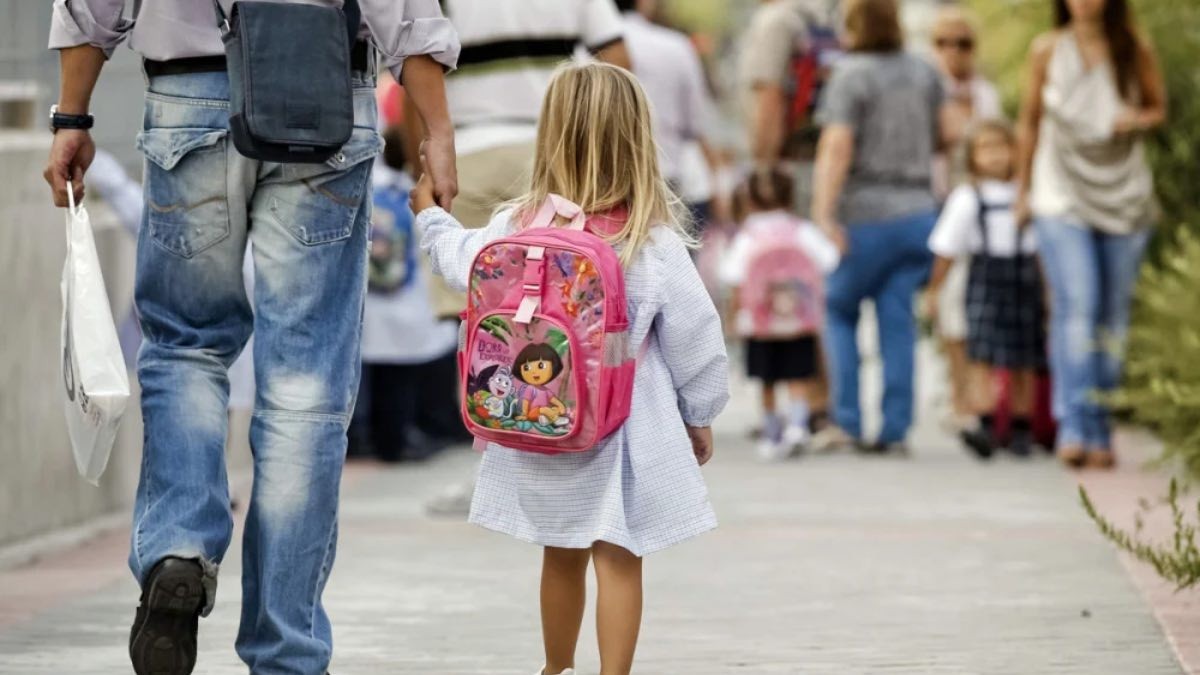 Cómo recibir un plus al IMV de la Seguridad Social por el cuidado de los hijos. padre con hija camino al colegio