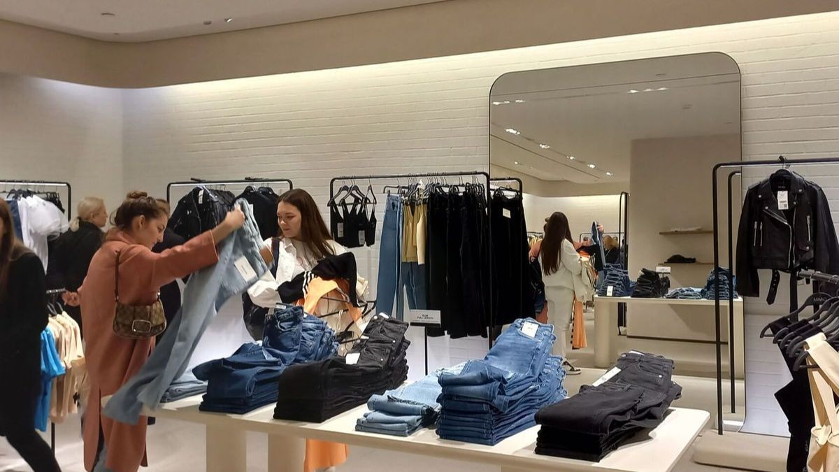 Una dependienta atiende a sus clientas en una tienda de ropa.