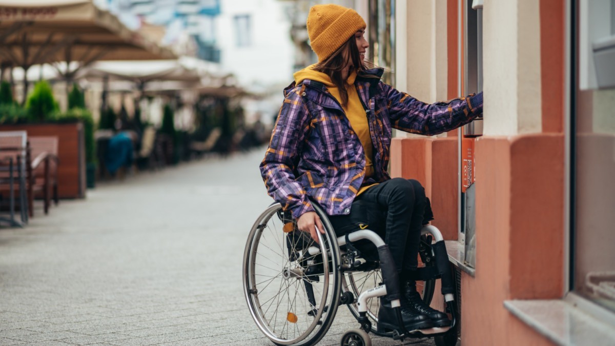 mujer en silla de ruedas sacando dinero del cajero