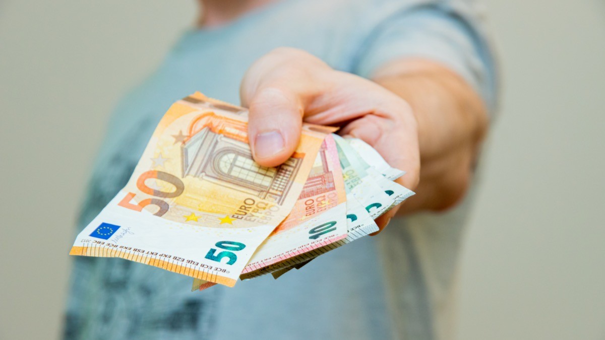 El Banco Santander regala hasta 400 euros con este único requisito antes de Navidad persona entregando dinero