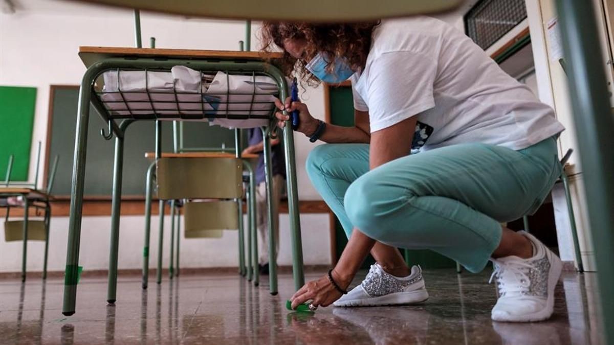 Una limpiadora trabaja en un aula de un colegio.