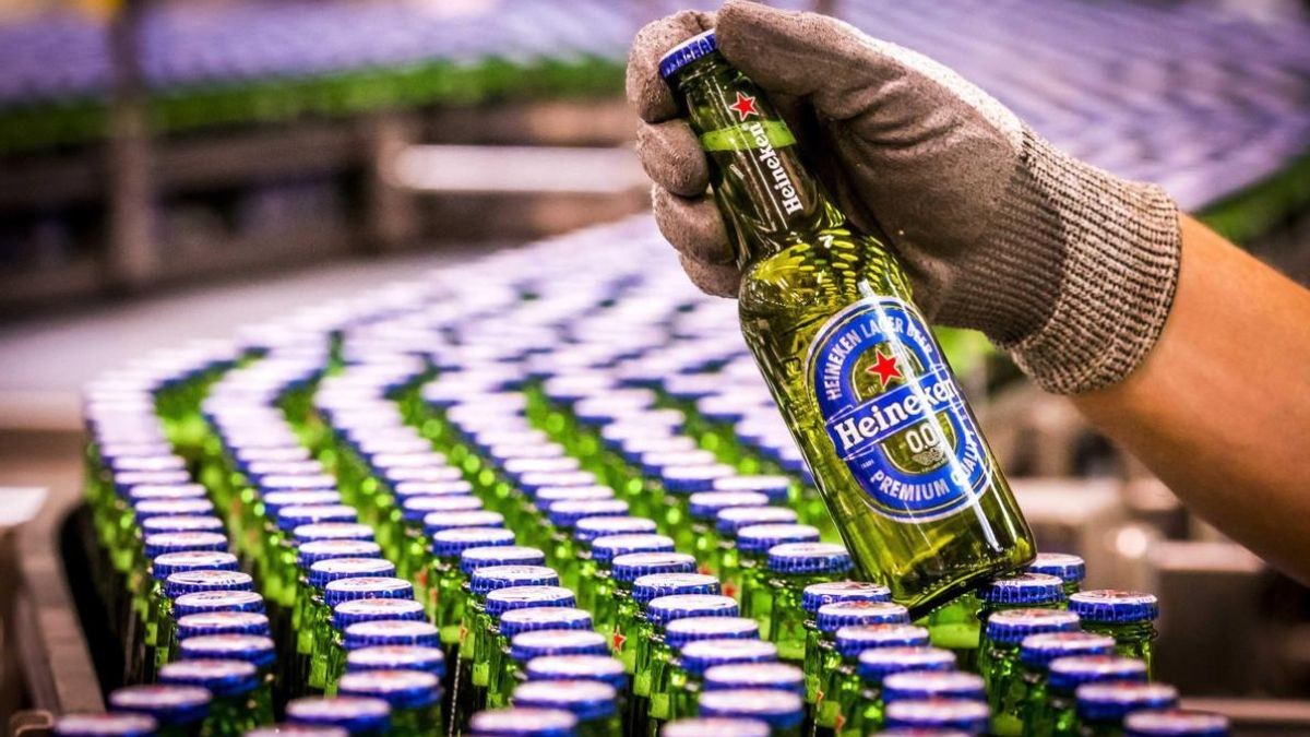 Heineken y sindicatos acuerdan un ERE para 127 empleados: la mayoría prejubilaciones Un trabajador con muestra un botellín de Heineken.