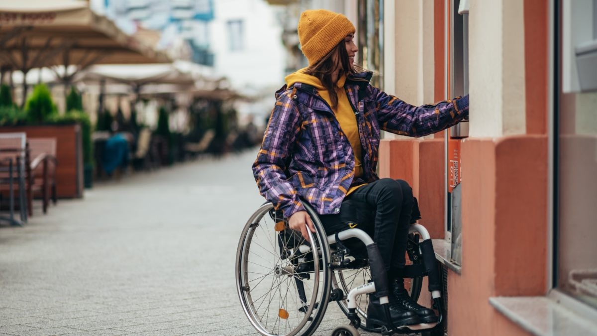 Una mujer en silla de ruedas frente a un cajero automático