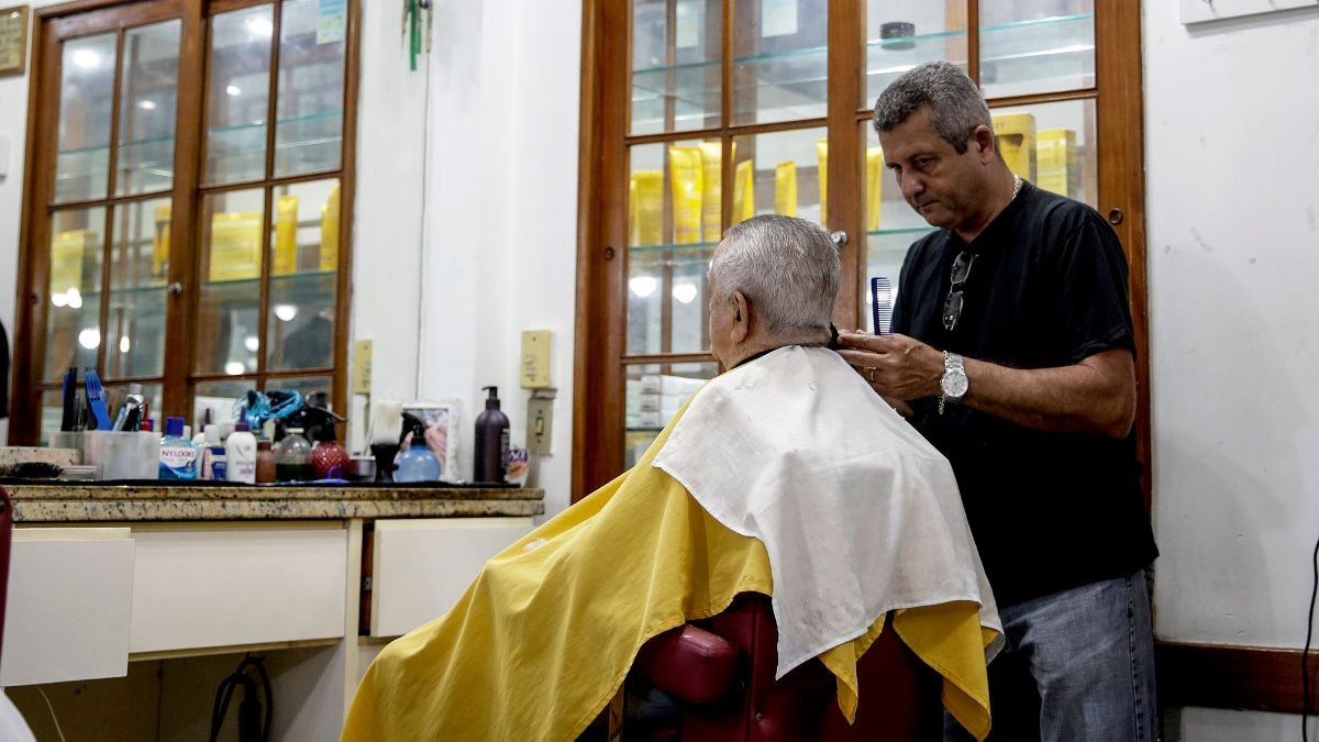 Un peluquero atiende a una persona mayor.