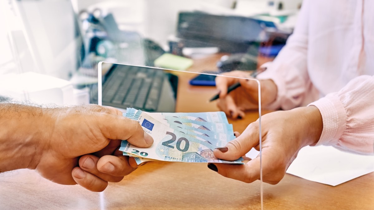 cajera entregando euros a un cliente en el banco