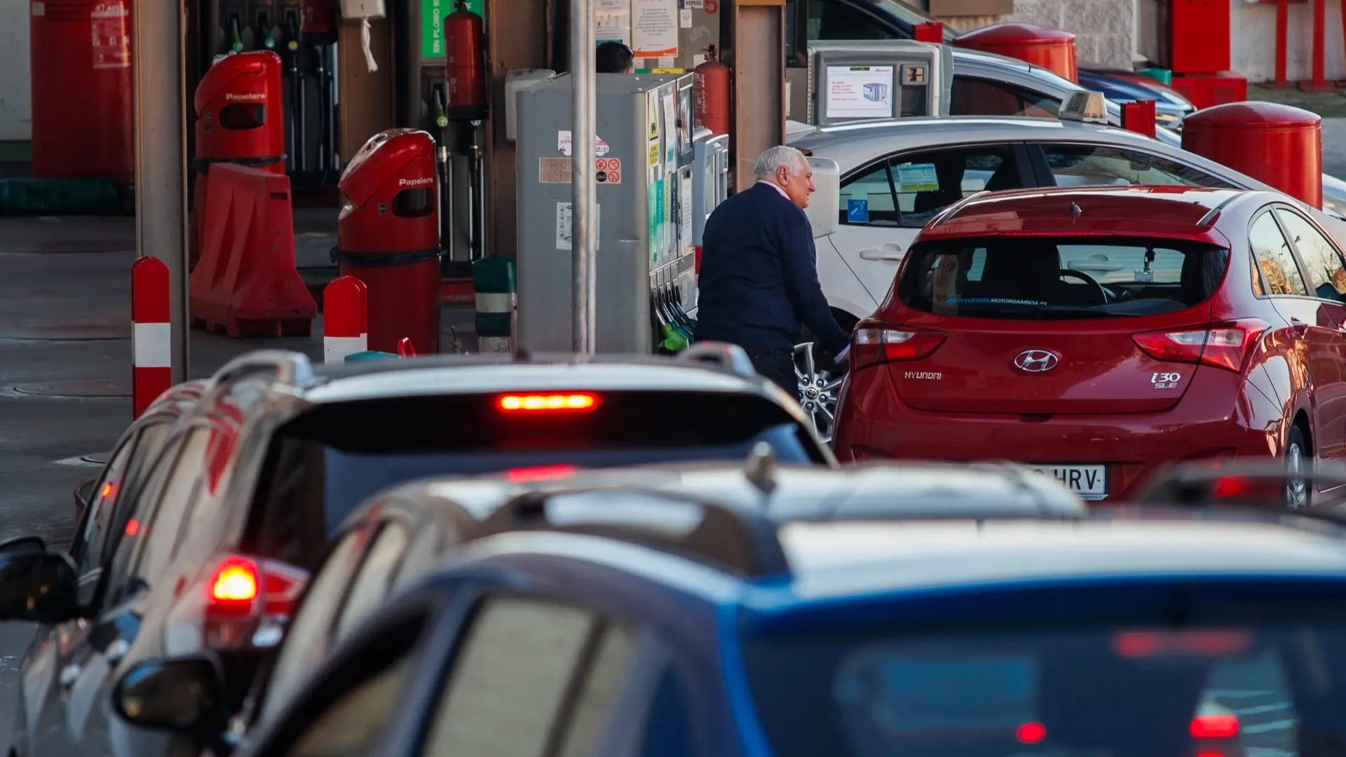 Un hombre repostando en una gasolinera Un hombre repostando en una gasolinera