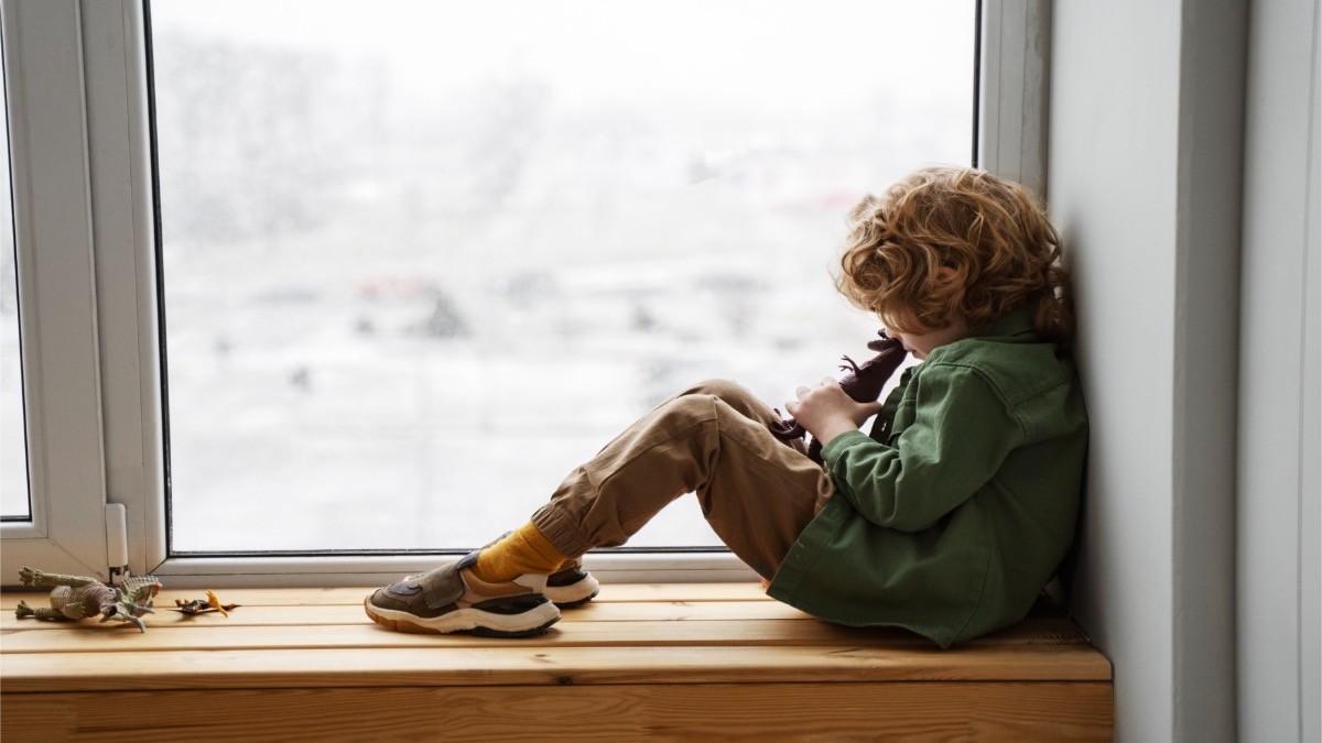 La Seguridad Social dice adiós a la pensión de orfandad a los 21 años en este caso, pero se puede retirar antes. niño huérfano junto a una ventana
