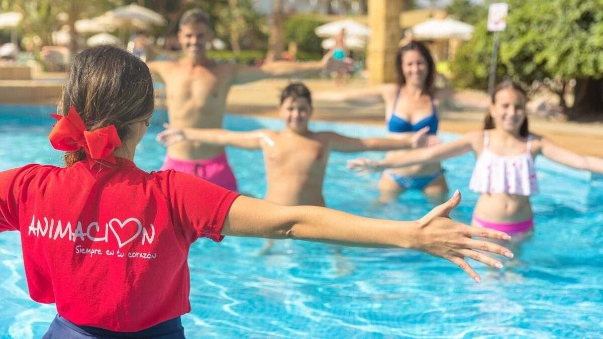 Hacen falta animadores para trabajar en hoteles, sin estudios y posibilidad de alojamiento gratis Una monitora con varios niños en la piscina de un hotel.
