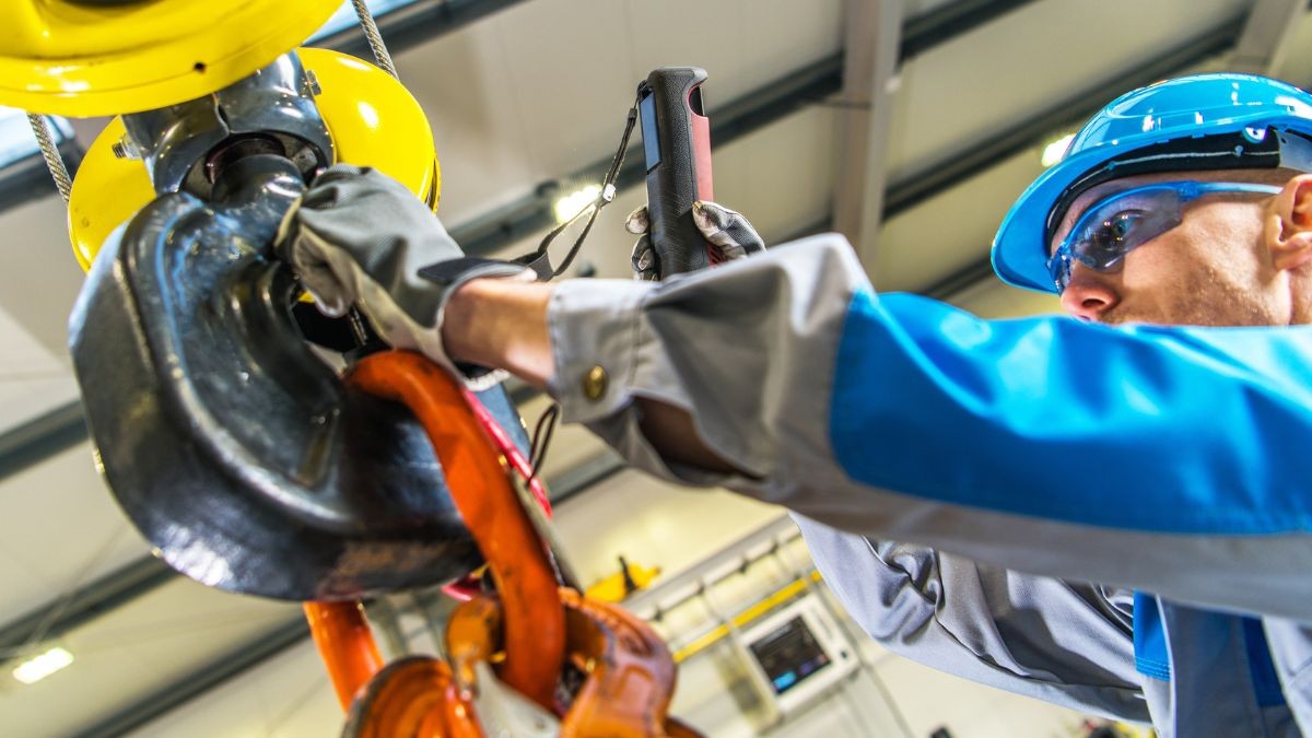 Un empleado mecánico trabaja con una polea de grúa.