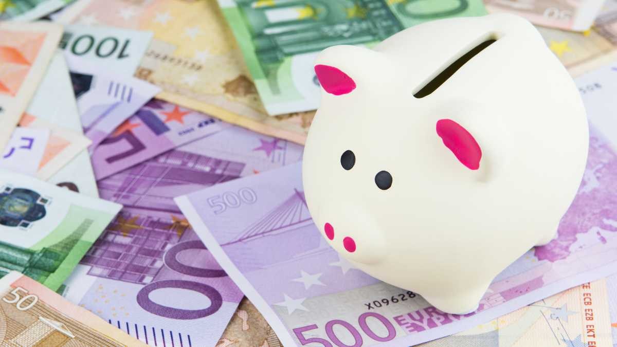 Hucha con forma de cerdito sobre billetes de euro