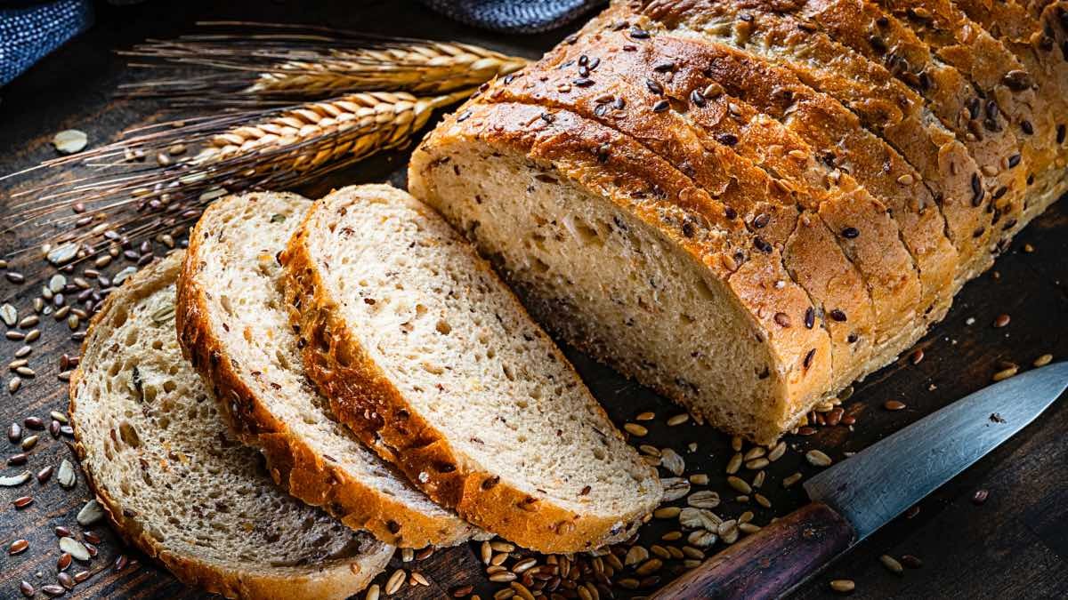 Di adiós al pan integral: el motivo por el que los médicos piden eliminarlo de la dieta. Pan integral cortado en rebanadas con un cuchillo al lado